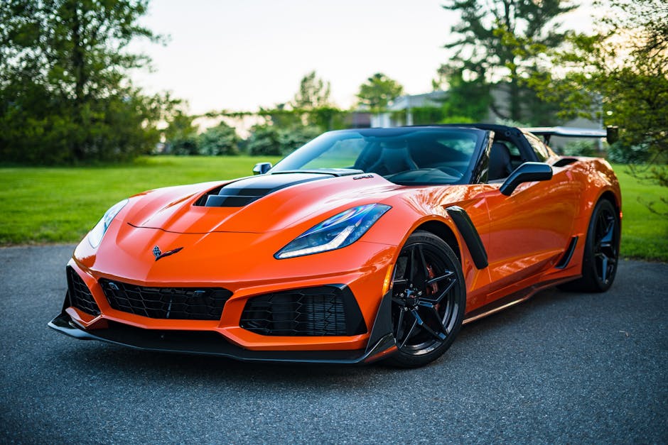 A sleek orange convertible sports car elegantly parked on a scenic outdoor road.
