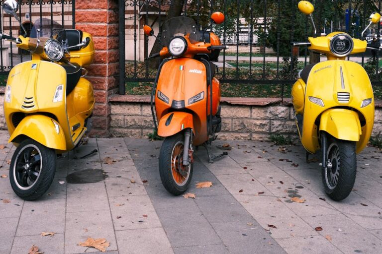 Bright yellow and orange scooters parked on a leaf-covered street in Istanbul, Turkey.