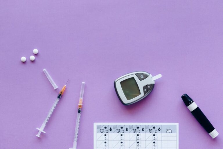 Flat lay of diabetes management tools including glucometer, syringes, and pills on purple background.