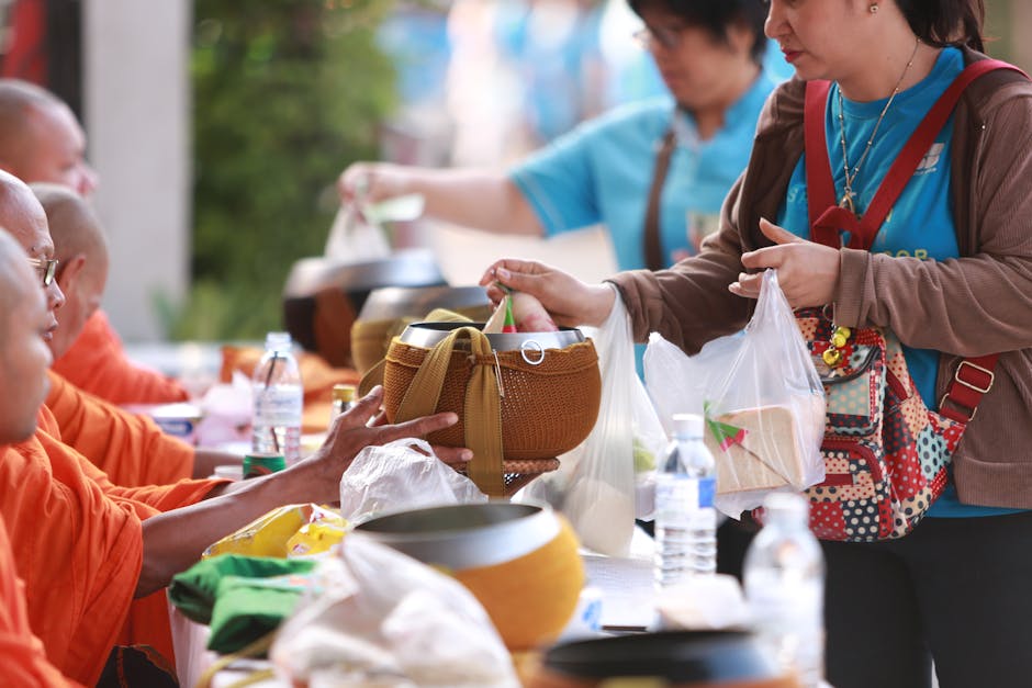 Women offer food and essentials to Buddhist monks in a traditional alms ceremony in Thailand.