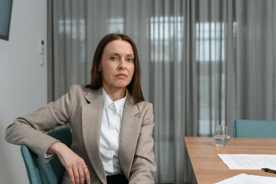 Professional woman in formal attire sitting confidently in a corporate office setting.