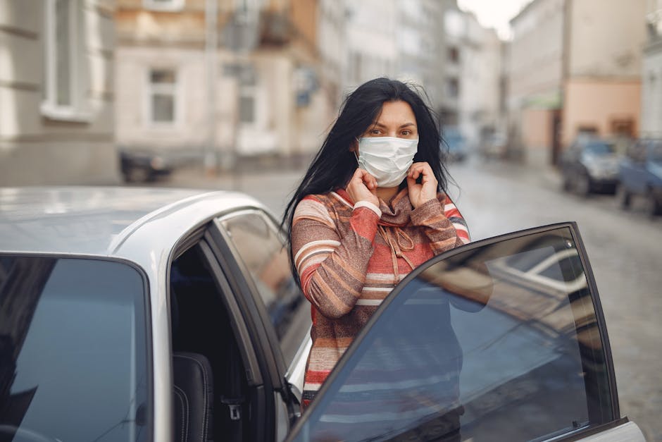 Woman in striped sweater adjusting mask while exiting car on city street during daytime.
