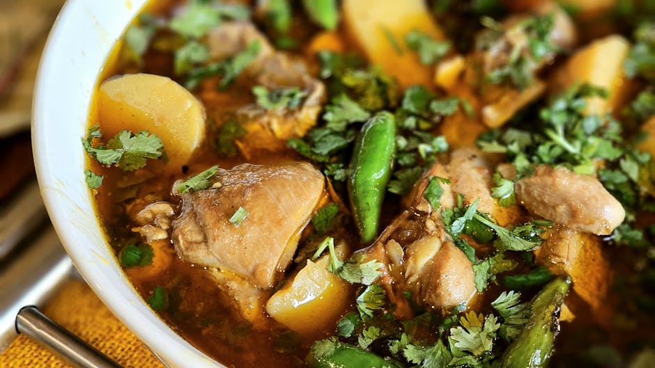Close-up of a flavorful chicken stew with potatoes, peppers, and garnish.