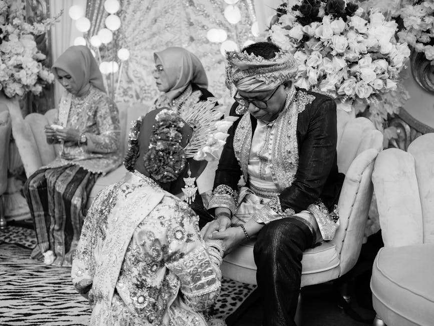A black and white photo of a cultural Indonesian wedding ceremony indoors.