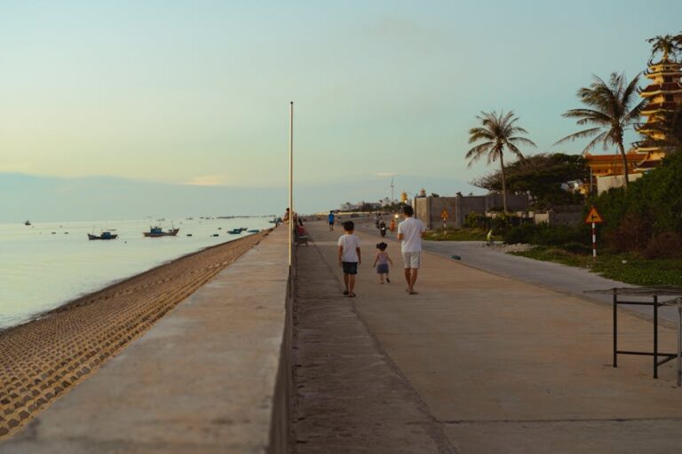 A peaceful walk along the beach in Bình Thuận, Vietnam with boats and palm trees in the background.