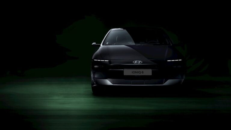 Front view of Hyundai Ioniq 6 electric car in a dimly lit studio setting, highlighting its sleek design.