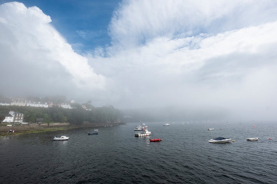 Misty seascape of Portree harbour with boats, showcasing the natural beauty of Scottish landscape.
