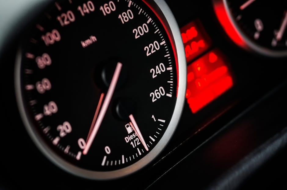 Detailed view of car speedometer and odometer with illuminated red gauges.