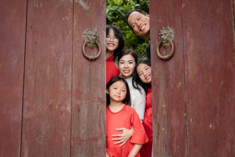 Happy family posing behind a wooden door amid greenery in Hội An, Vietnam.