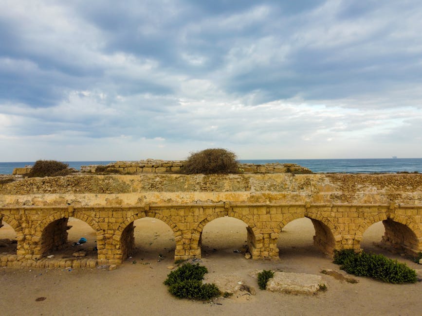 Discover the historic Roman aqueduct in Caesarea, set against a dramatic sky and serene seascape.