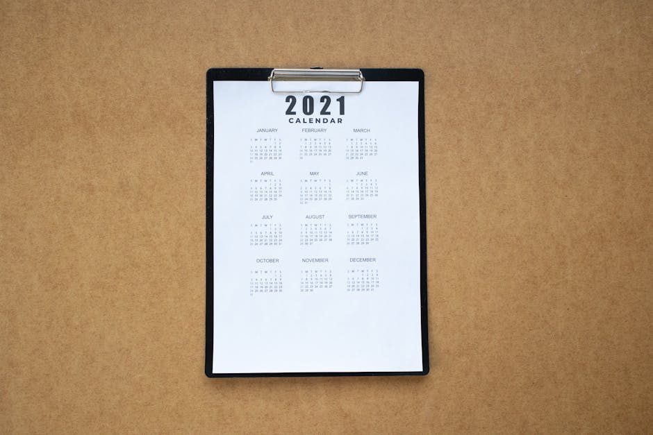 Top-down view of a minimalist 2021 calendar on a clipboard with brown background.