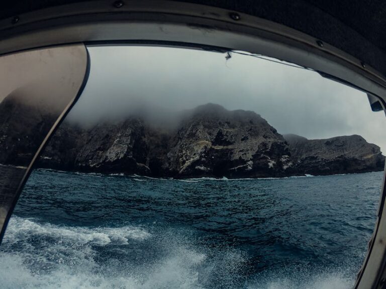 Scenic view of rocky island with mist from a boat. Dramatic and moody seascape.