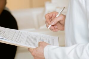 A medical professional in a white coat examines a clipboard with patient documents.
